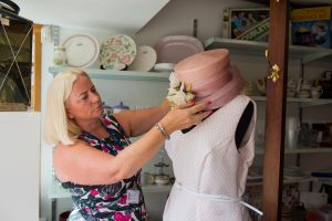 A woman positions a hat on a mannequin at a St Clare shop