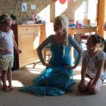 Princess Elsa kneeling with two little girls