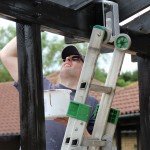 Man on a ladder with a paint pot and brush