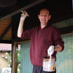 Man on a ladder holding a paint pot and brush