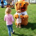 Little girl cuddling bear mascot