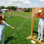 Girl throwing wet sponge at boy in stocks