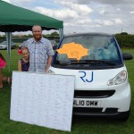 Man and girl posing next to car filled with balloons