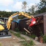 Digger demolishing shed