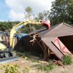 Digger demolishing shed