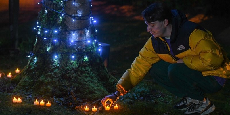 A Light up a Life attendee placing their candle by the Light up a Life tree.
