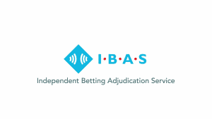 Independent Betting Adjudication Service (IBAS) logo can be seen. The logo features a blue diamond with two soundwave icons inside of it. Beside it "IBAS" can be read in blue with red dots in between each letter. Below it "Independent Betting Adjudication Service" can be read in a grey font. All are in a sans-serif font.