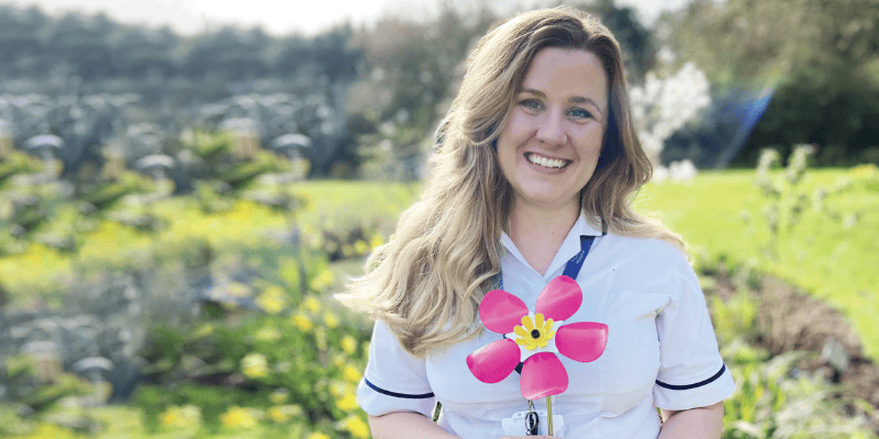 Image of physiotherapist for St Clare holding the limited-edition pink Forever Flower. She smiles at the camera.
