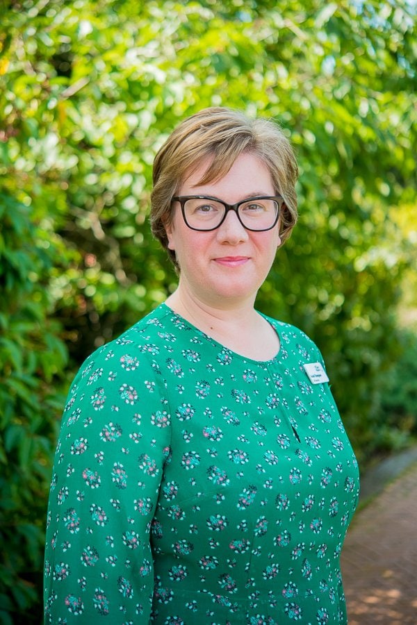 Image of St Clare Hospice CEO Sarah Thompson in a green dress. She smiles, mouth closed, at camera.