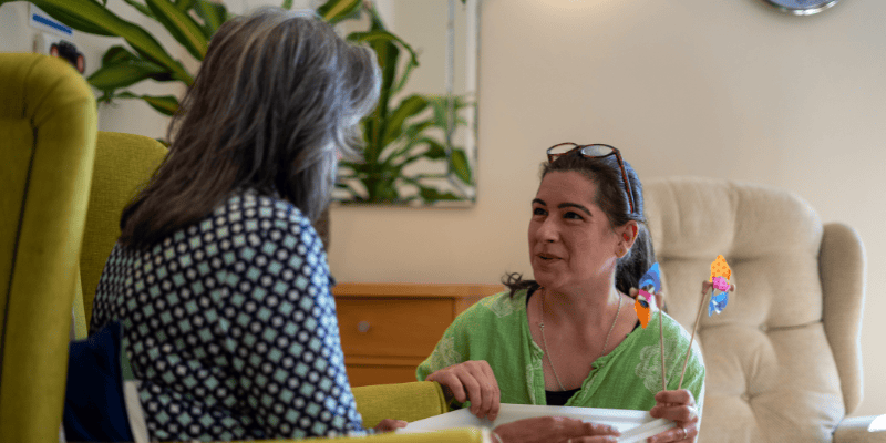 Dementia support volunteer Diane is pictured speaking to someone in their own home.