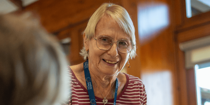 Photo of Café Clare volunteer Carol smiling while she speaks to someone at the café.
