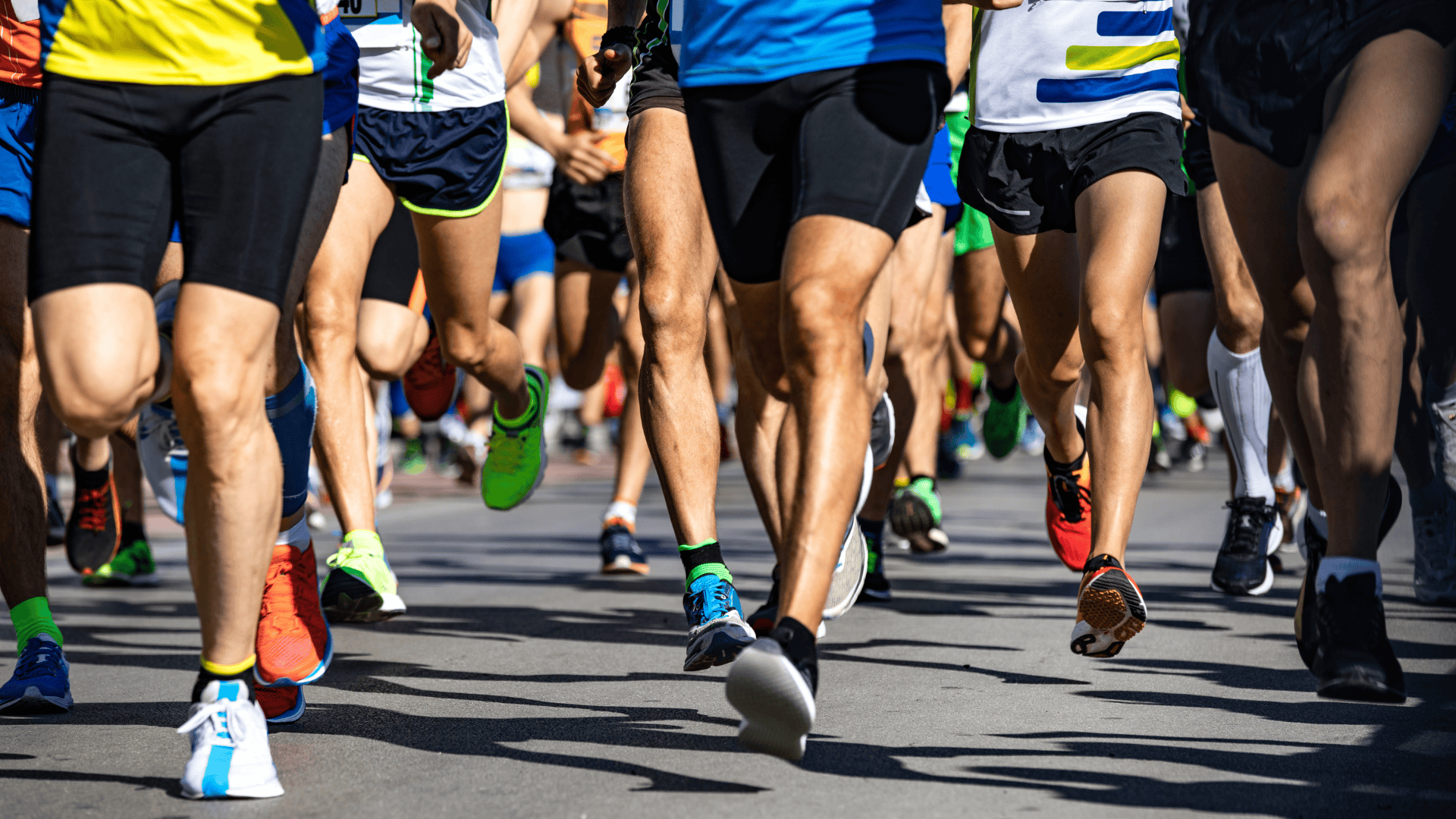 Photo of people's legs as they run along a road.