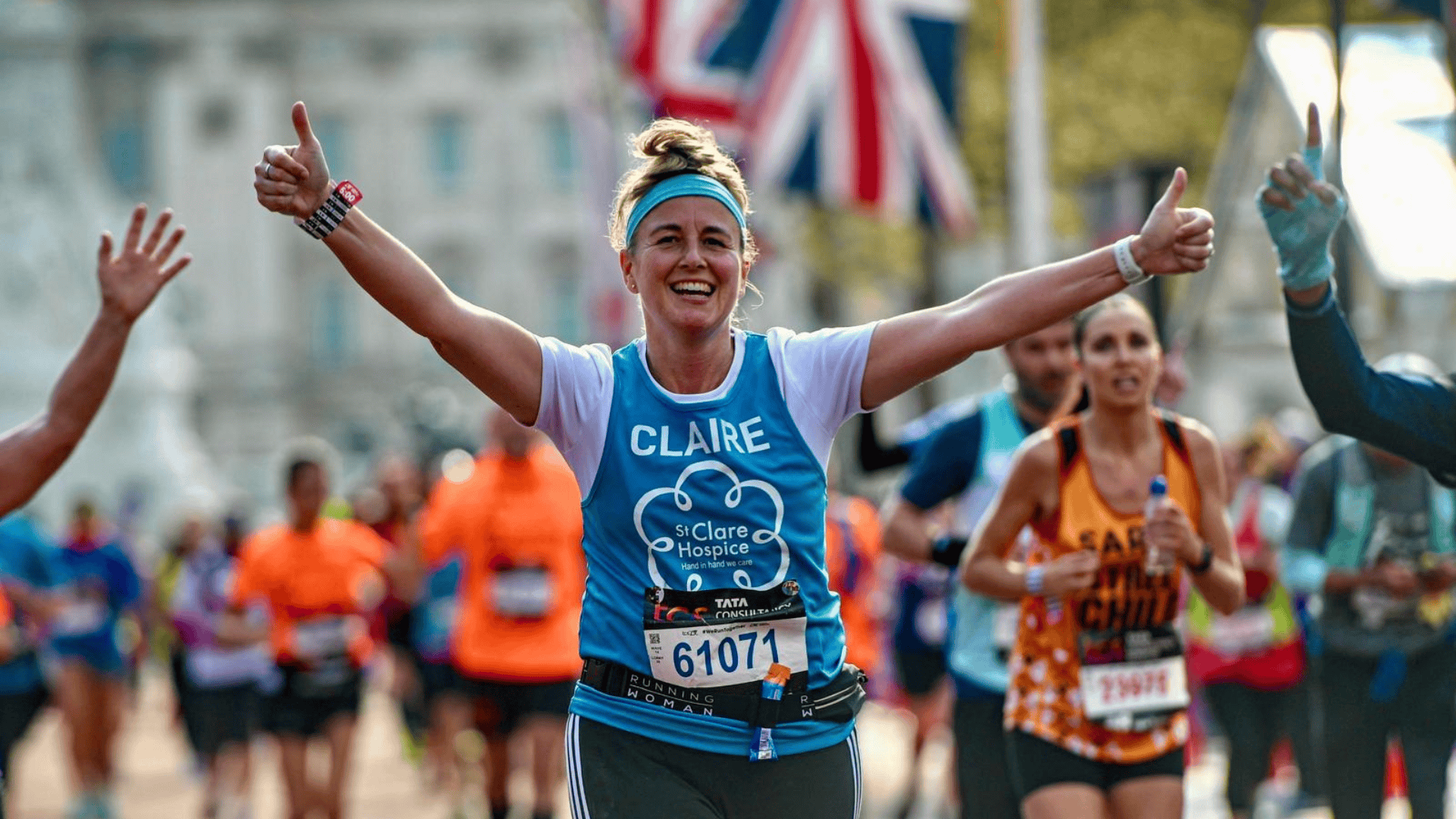 Photo of St Clare Hospice runner wearing branded vest smiling at the camera while running in London.