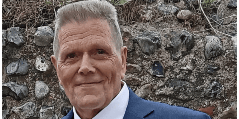 Alan pictured smiling at the camera in a suit.